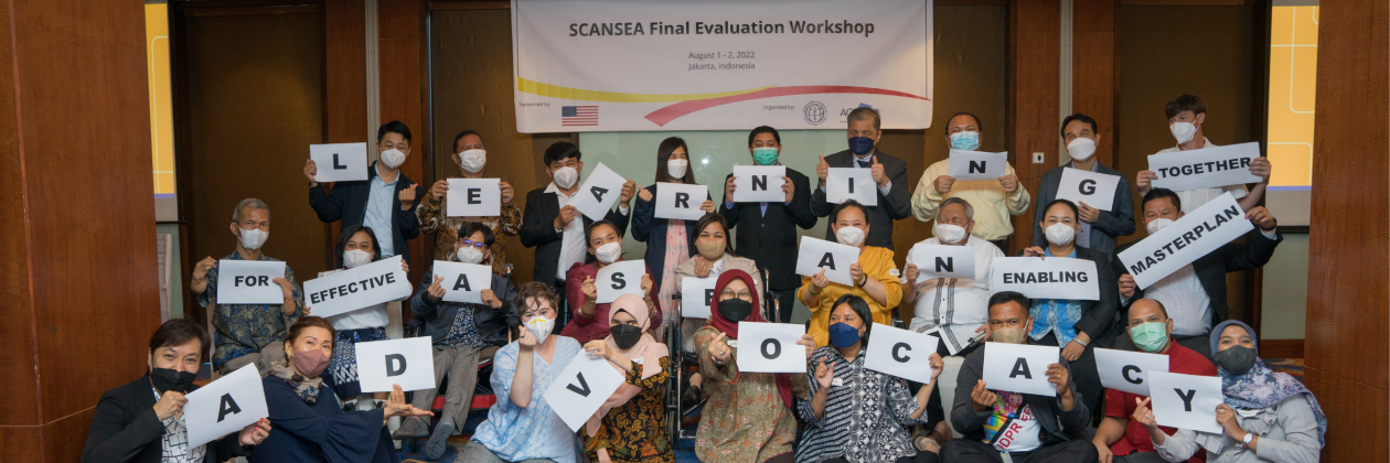 AGENDA Evaluation Event, participants hold letters in front of sign. 