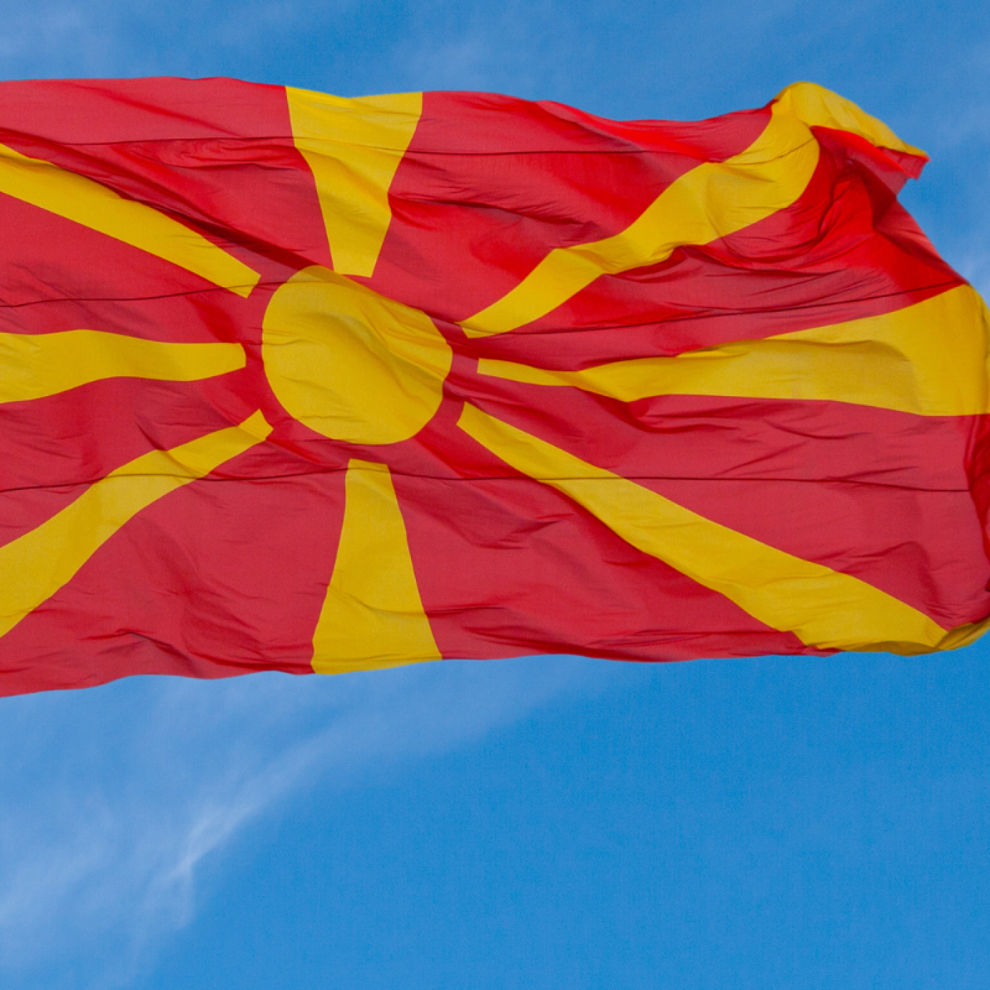 Flag of North Macedonia flying in blue sky.